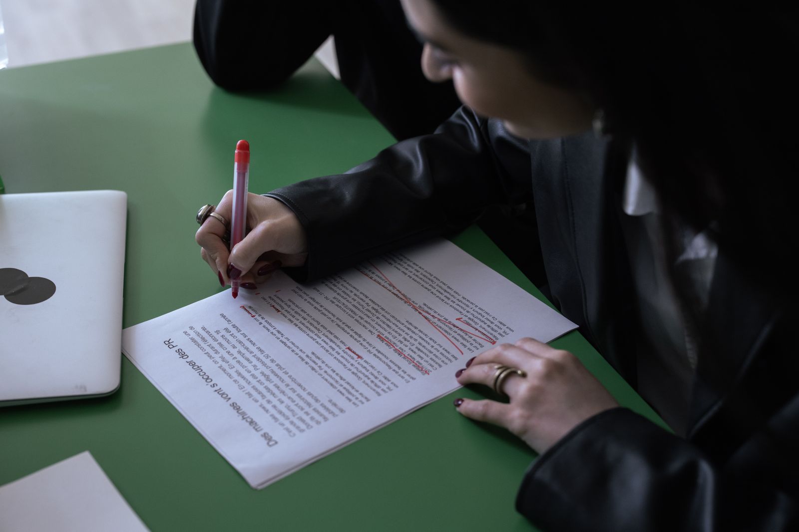 Cover photo: someone marking up a printed draft in red pen, a closed laptop beside them